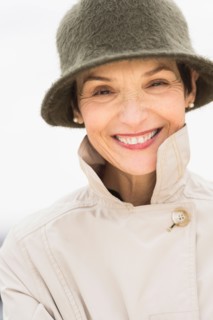 Portrait of smiling woman wearing raincoat and hat.