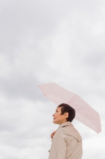 Woman wearing raincoat and holding umbrella.