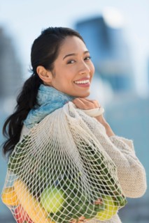 Portrait of smiling young woman with grocery shopping bag.