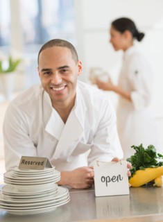 Couple during preparations in kitchen of their own restaurant.