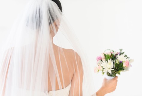 Portrait of bride in veil holding bouquet.