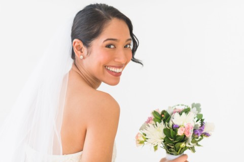 Portrait of bride in veil holding bouquet.
