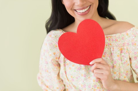 Young woman holding red paper heart.