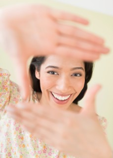 Young woman looking through hand frame.