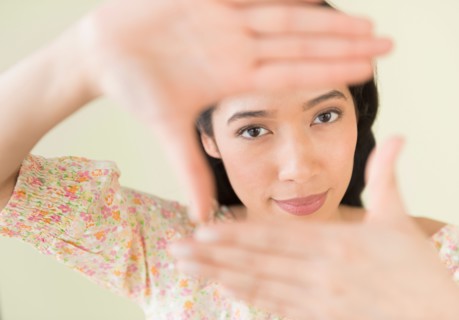 Young woman looking through hand frame.