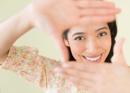 Young woman looking through hand frame.