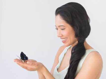 Young woman holding butterfly.