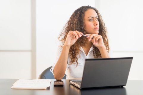 Office worker sitting by desk with laptop.