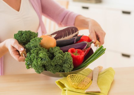 Mature woman holding wok with vegetables