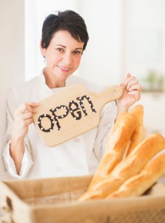 Portrait of mature woman holding basket with baguettes