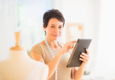 Portrait of mature woman with clothing bust using digital tablet