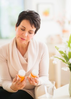 Portrait of mature woman looking at pill bottles