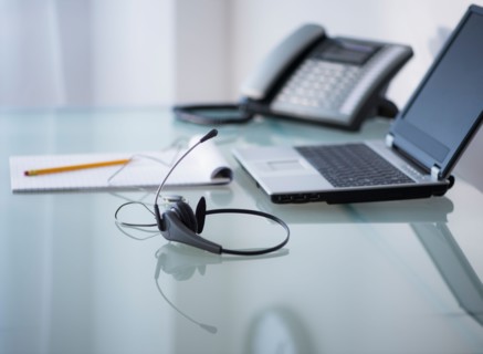 View of headset, telephone, laptop and paper material on desk