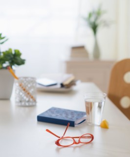 View of spectacles, personal organizer and glass of water on table