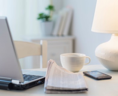 View of newspaper, laptop, mobile phone and cup