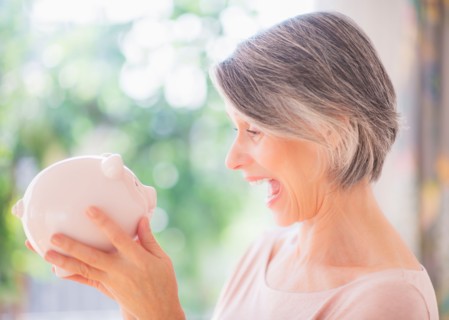 Portrait of excited woman holding piggy bank