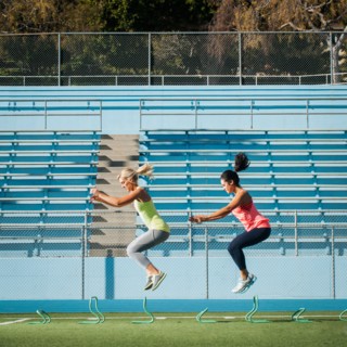 Two women jumping over hurdles