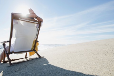 Rear view of woman relaxing on chair at beach