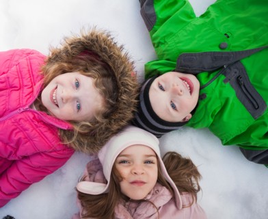 Directly above portrait of three children (2-3, 4-5) lying on snow