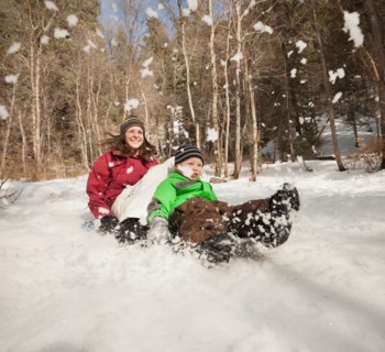 Young woman sledding with boy (4-5)