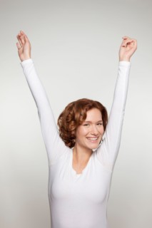 Studio shot portrait of young woman in white blouse with arms raised