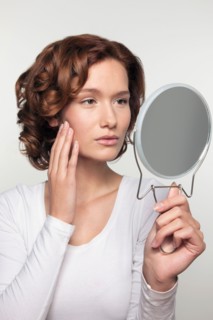 Studio shot portrait of young woman watching herself in mirror