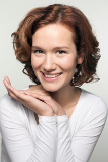 Studio shot portrait of young woman in white blouse with hands clasped