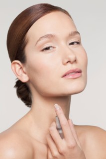 Studio shot portrait of young woman holding perfume