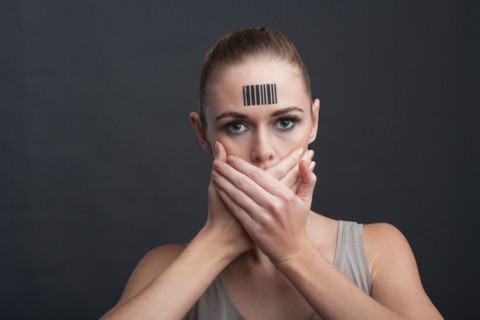 Studio shot of young woman covering her mouth