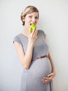 Studio Shot of pregnant woman eating apple