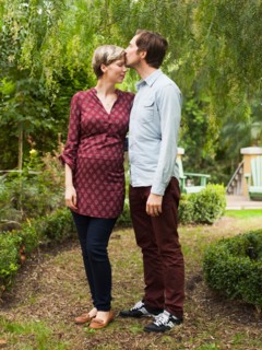 Pregnant couple embracing and kissing in garden
