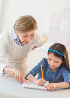 Teacher helping schoolgirl (8-9) at school.