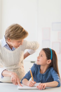 Teacher helping schoolgirl (8-9) at school.