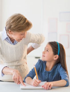 Teacher helping schoolgirl (8-9) at school.