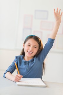Portrait of schoolgirl (8-9) raising hand.