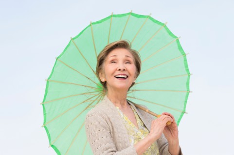 Portrait of senior woman holding green parasol.