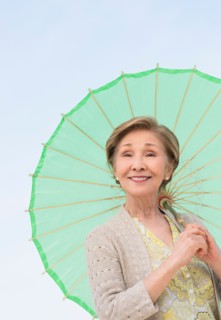 Portrait of senior woman holding green parasol.