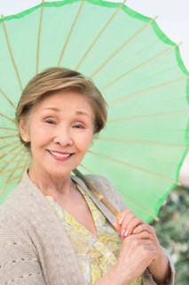 Portrait of senior woman holding green parasol.