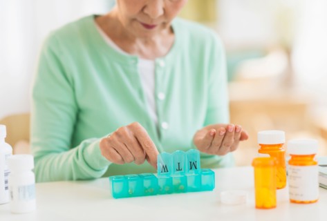 Senior woman organizing medicine in box.