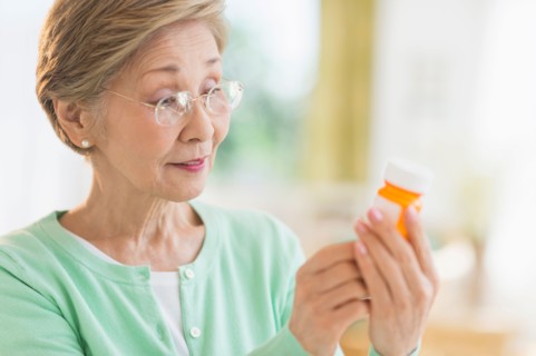 Senior woman reading medicine label.