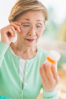 Senior woman reading medicine label.