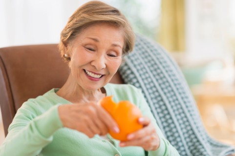 Portrait of senior woman peeling orange.