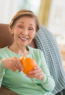 Portrait of senior woman peeling orange.