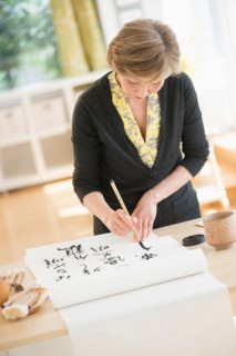 Senior woman painting japanese symbols.