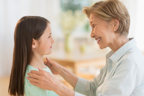 Granddaughter (8-9) and grandmother smiling to each other.
