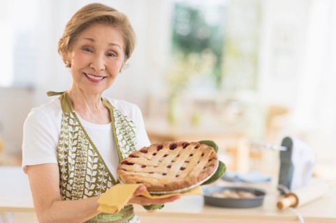 Senior woman holding freshly baked cake.