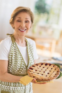 Senior woman holding freshly baked cake.