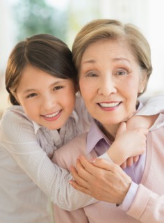 Granddaughter (8-9) embracing grandmother.
