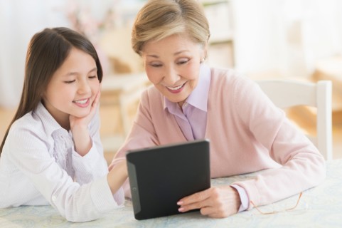 Granddaughter (8-9) and grandmother using digital tablet.