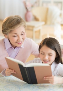 Granddaughter (8-9) and grandmother reading book.